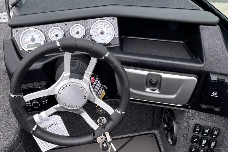 Slide: The Image of Steering wheel and dashboard of 2026 Lund 1975 Pro-V boat, featuring modern gauges and controls. - 8