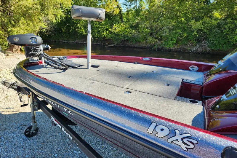 Slide: The Image of 2013 Triton 19XS boat on trailer, parked near a river, surrounded by trees. - 10