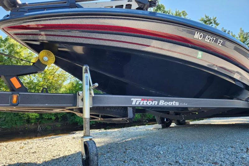 Slide: The Image of 2013 Triton 19XS boat on trailer, parked on gravel near trees. - 20