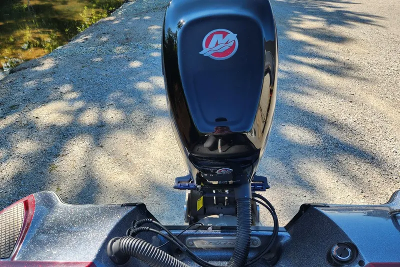 Slide: The Image of 2013 Triton 19XS boat engine, parked on a gravel path near water. - 23