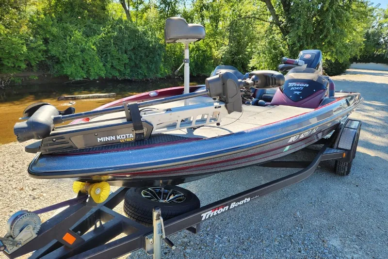 Slide: The Image of 2013 Triton 19XS boat with Minn Kota Ultrex motor on trailer by riverbank. - 8