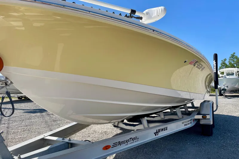 Slide: The Image of 2022 Hewes Redfisher 21 boat on trailer, yellow hull, clear blue sky background. - 12