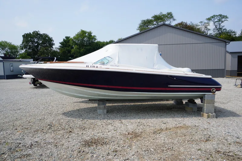 The Image of 2007 Chris-Craft Corsair 28 boat on blocks, covered, in a gravel lot. - 0
