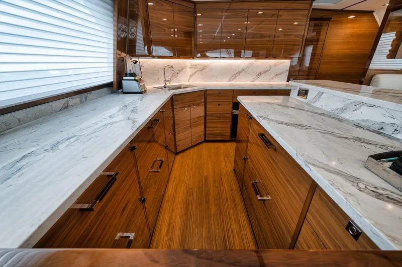Slide: The Image of Luxurious kitchen interior of 2024 Viking 72 Skybridge yacht with marble countertops and wood cabinetry. - 11