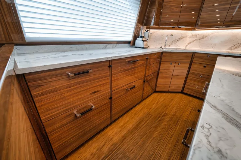 Slide: The Image of Luxurious kitchen interior of 2024 Viking 72 Skybridge yacht with wood cabinetry and marble countertops. - 12
