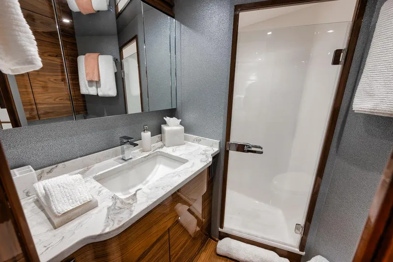 Slide: The Image of Luxurious bathroom in 2024 Viking 72 Skybridge yacht with marble countertop and glass shower. - 19