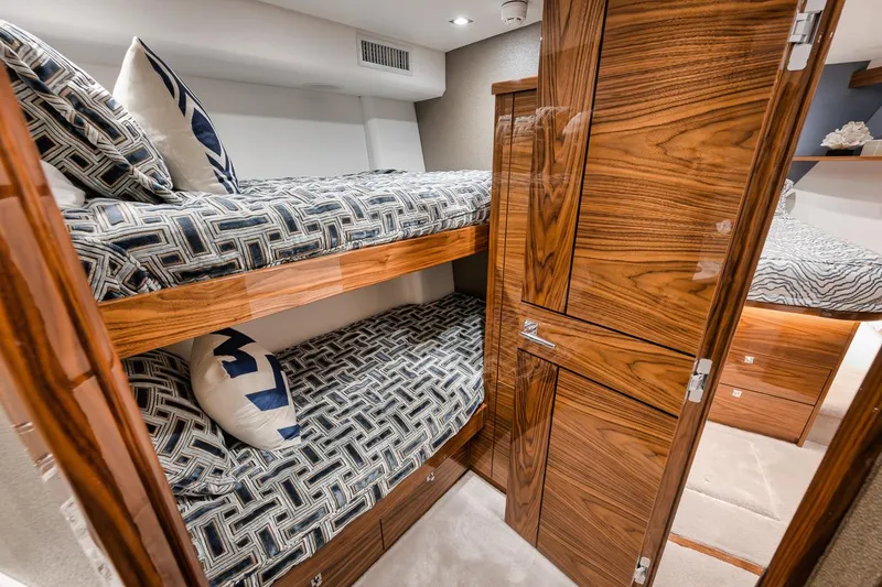 Slide: The Image of Luxurious 2024 Viking 72 Skybridge yacht cabin with wooden bunk beds and patterned bedding. - 23