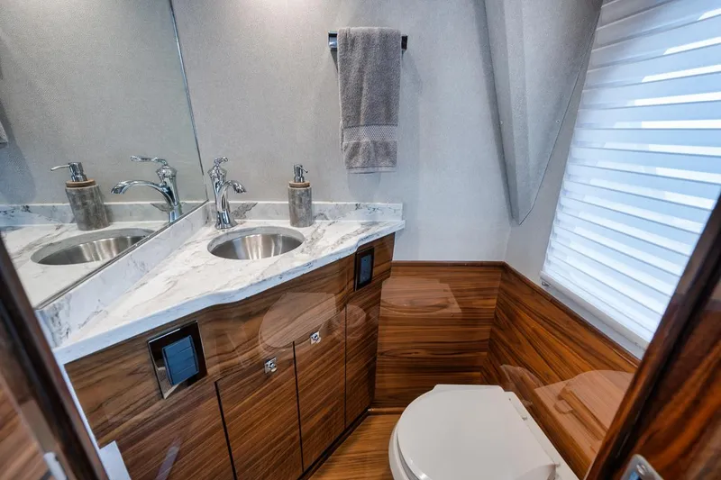 Slide: The Image of Luxurious bathroom in 2024 Viking 72 Skybridge yacht with marble countertop and wood accents. - 24