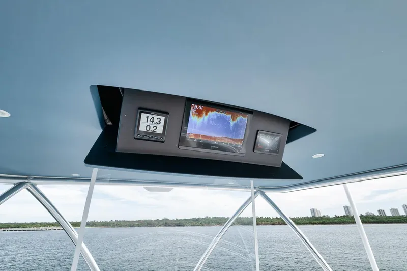 Slide: The Image of 2024 Viking 72 Skybridge navigation display with digital gauges and radar, overlooking serene waters. - 40