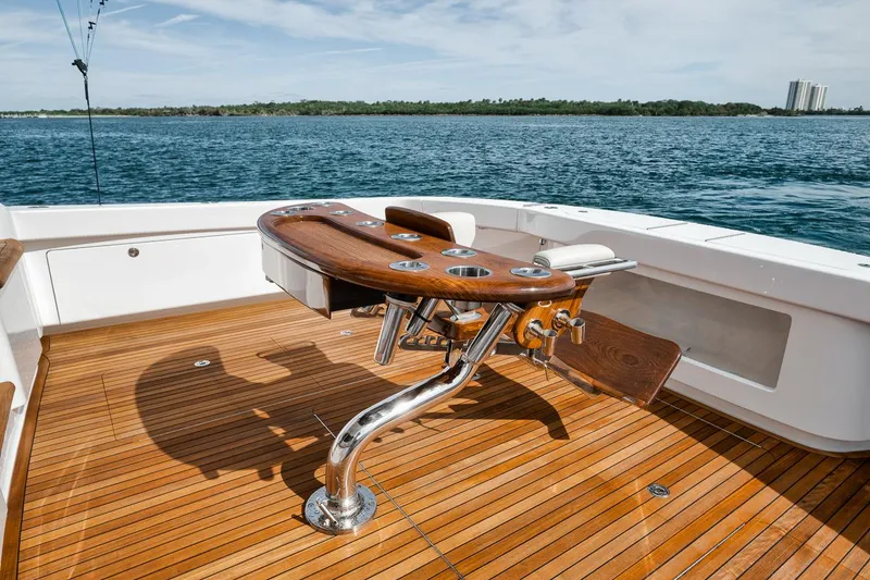 Slide: The Image of 2024 Viking 72 Skybridge yacht deck with fishing chair, overlooking serene waters. - 46