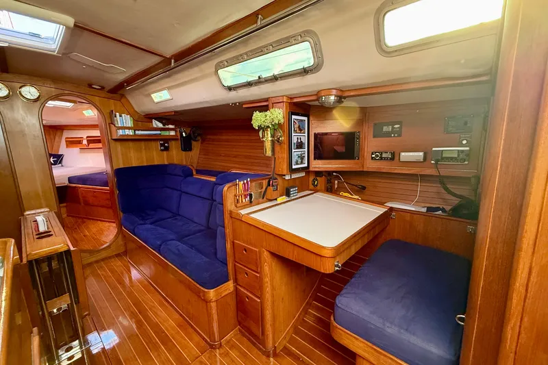 Slide: The Image of Luxurious 1991 J/Boats interior with wood finish, blue seating, and navigation station. - 10