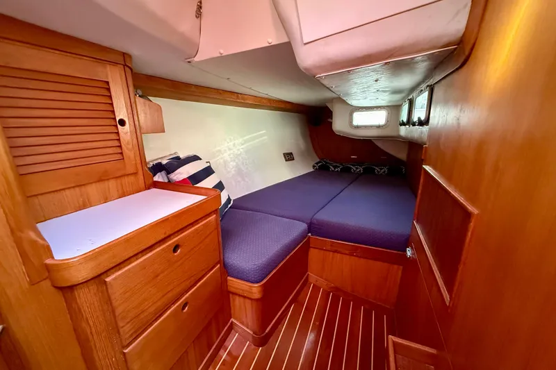 Slide: The Image of Cozy cabin interior of a 1991 J/Boats model with wooden furnishings and blue bedding. - 13