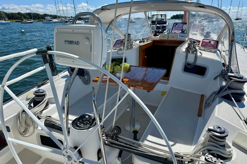 Slide: The Image of Cockpit of a 1991 J/Boats sailboat, featuring a wooden table and navigation equipment. - 2