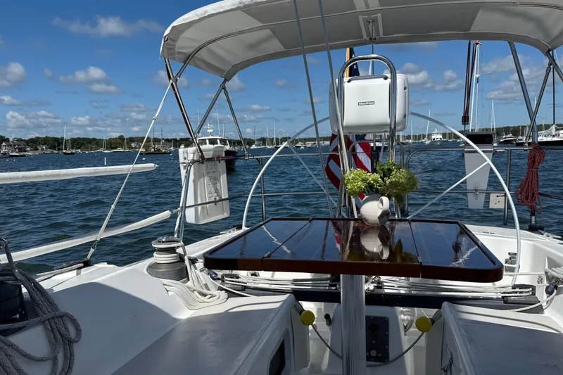 Slide: The Image of Cockpit view of a 1991 J/Boats sailboat with polished table and scenic harbor backdrop. - 21