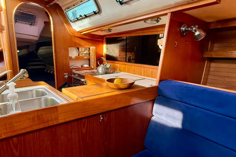 Slide: The Image of Luxurious wooden interior of a 1991 J/Boats model, featuring a cozy kitchen and seating area. - 22