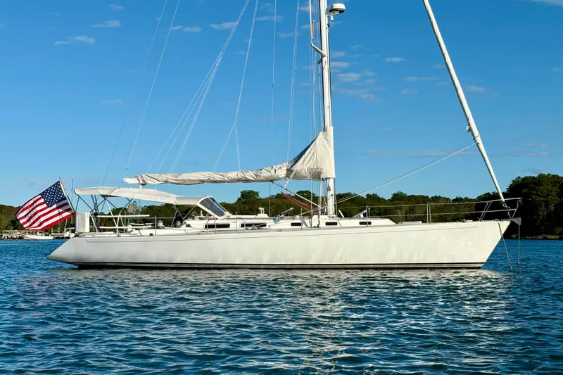 Slide: The Image of Sailboat on water, 1991 J/Boats J/47, with American flag, clear sky background. - 25