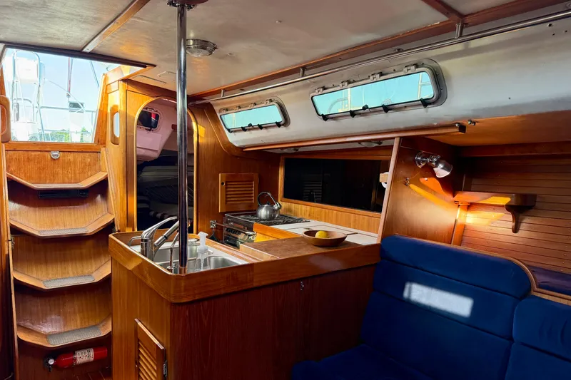 Slide: The Image of Interior of a 1991 J/Boats yacht with wooden cabinetry and blue seating. - 7