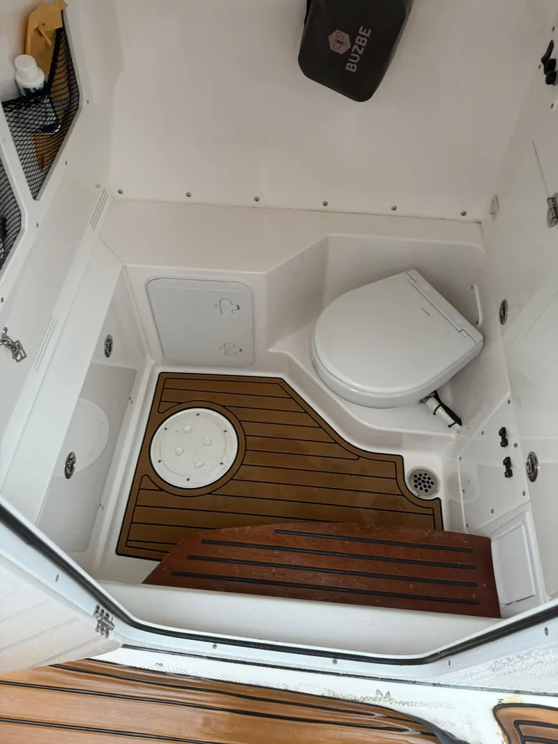 Slide: The Image of 2023 Everglades 285 Center Console boat interior with toilet and wooden flooring. - 12