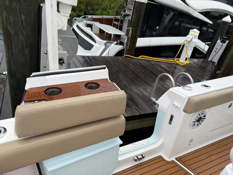 Slide: The Image of 2023 Everglades 285 Center Console boat docked, featuring cushioned seating and cup holders. - 15