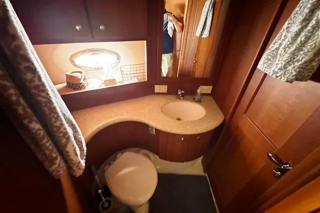 Slide: The Image of 2004 Silverton 35 MY Aft Cabin Motoryacht bathroom with sink, toilet, and wooden cabinetry. - 41