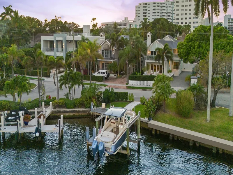 Slide: The Image of 2023 Chris-Craft Launch 31 GT docked by waterfront homes, surrounded by lush greenery. - 6