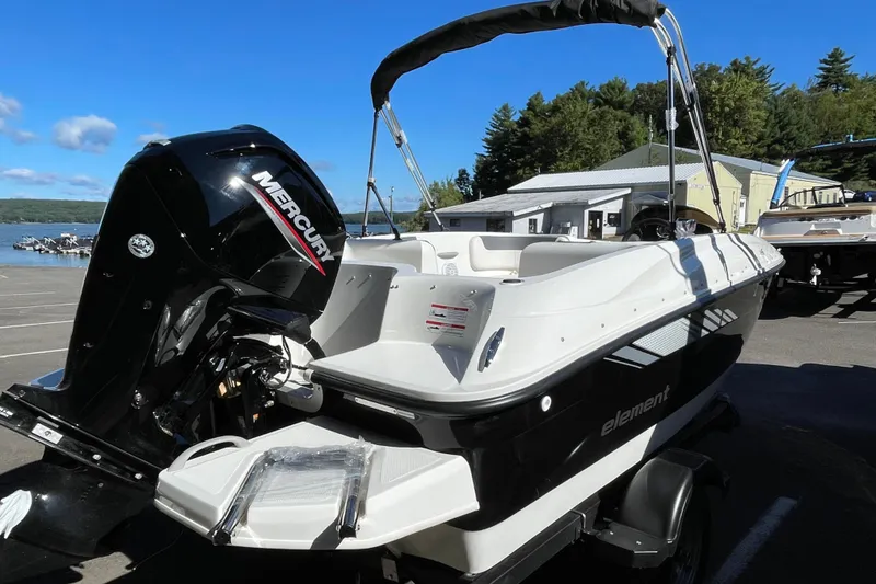 Slide: The Image of 2026 Bayliner Element E16 boat with Mercury engine, parked near a lake under clear blue sky. - 3