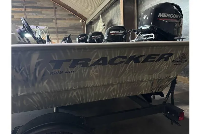 Slide: The Image of 2024 Tracker Grizzly 1648 boat with Mercury engines in a garage setting. - 6