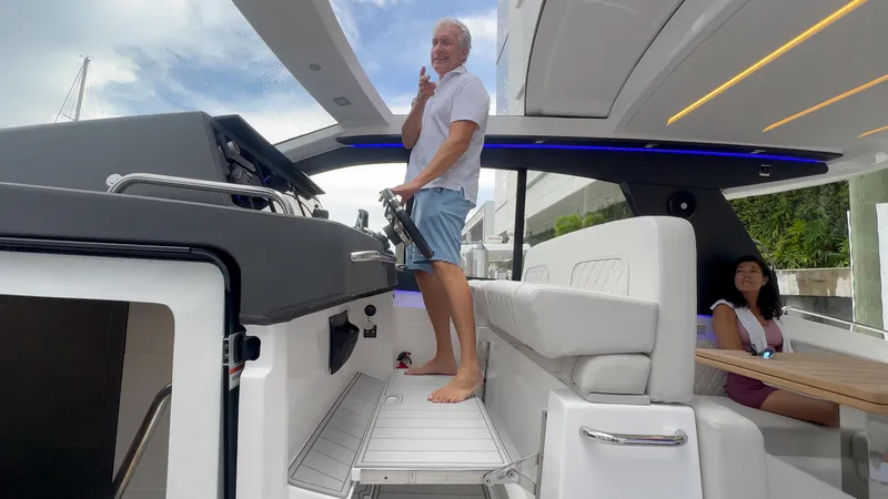 Slide: The Image of Man steering 2025 Schaefer 375 yacht, woman seated, modern interior design. - 13