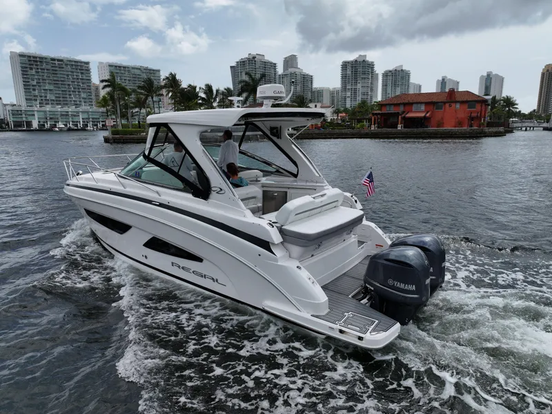 The Image of 2021 Regal 33 XO boat cruising near city waterfront with Yamaha engines. - 0