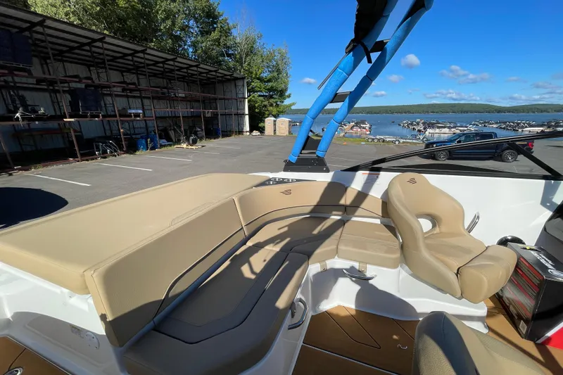 Slide: The Image of 2026 Bayliner V20i boat interior with beige seating, dockside view, and clear blue sky. - 3
