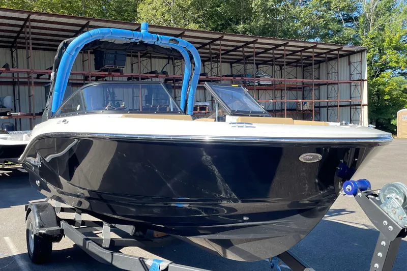 Slide: The Image of 2026 Bayliner V20i boat on trailer, parked outdoors near storage facility. - 6