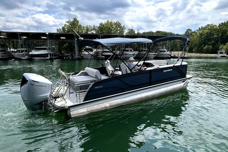 Slide: The Image of 2025 Godfrey Monaco 255 DFL pontoon boat cruising on a serene lake. - 3