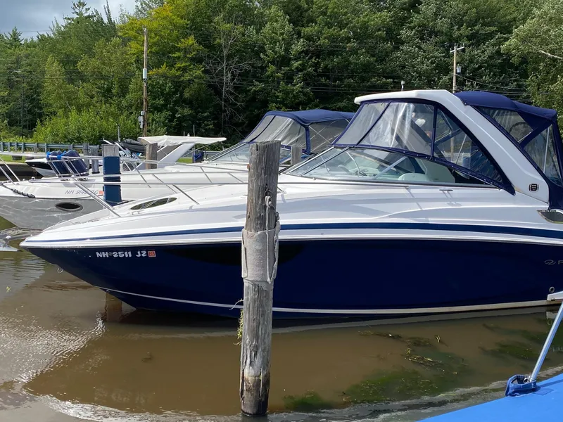 The Image of 2019 Regal 28 Express boat docked in a marina, surrounded by lush greenery. - 0