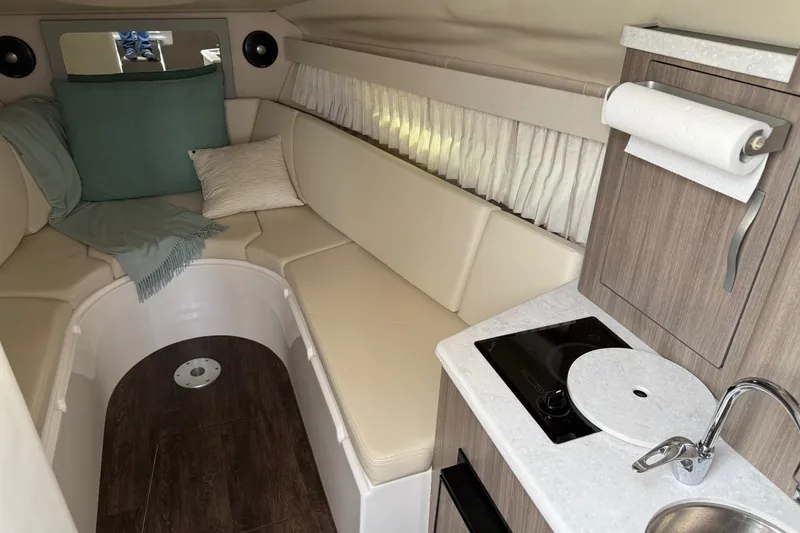 Slide: The Image of 2019 Regal 28 Express cabin interior with cozy seating and compact kitchenette. - 18