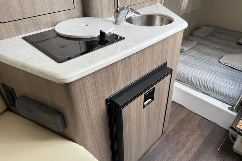 Slide: The Image of Compact kitchen area in 2019 Regal 28 Express boat with stove, sink, and bed. - 21