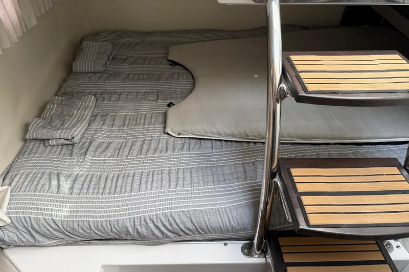 Slide: The Image of Cozy cabin interior of 2019 Regal 28 Express with striped bedding and wooden steps. - 22