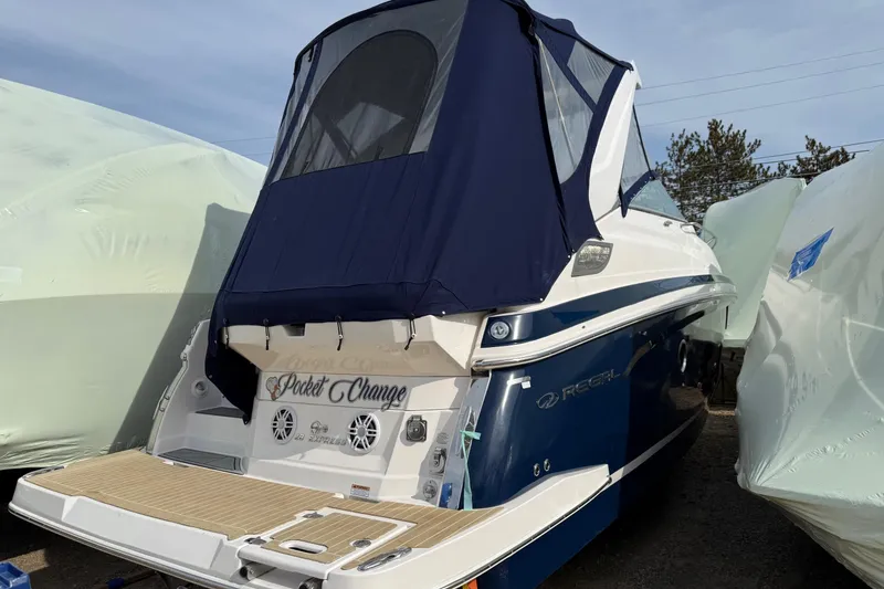 Slide: The Image of 2019 Regal 28 Express boat with blue canopy, docked and covered for storage. - 27