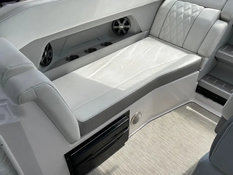 Slide: The Image of 2019 Regal 28 Express boat interior with cushioned seating and built-in cup holders. - 7