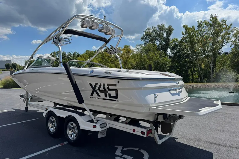 Slide: The Image of 2006 MasterCraft X-45 boat on trailer, parked near a scenic pond. - 5