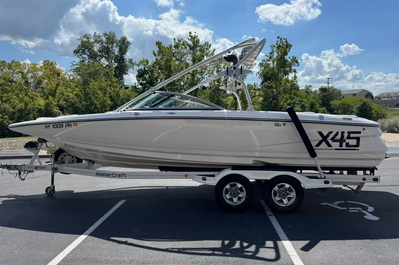 Slide: The Image of 2006 MasterCraft X-45 boat on trailer, parked outdoors under a sunny sky. - 6