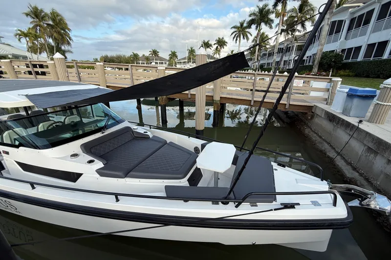 Slide: The Image of 2020 Axopar 37 Sun-Top boat interior with seating and table, docked by the water. - 34