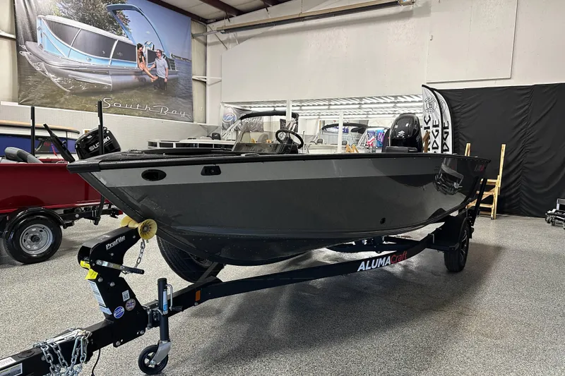 Slide: The Image of 2026 Alumacraft Competitor 185X Side Console boat displayed indoors on a trailer. - 3