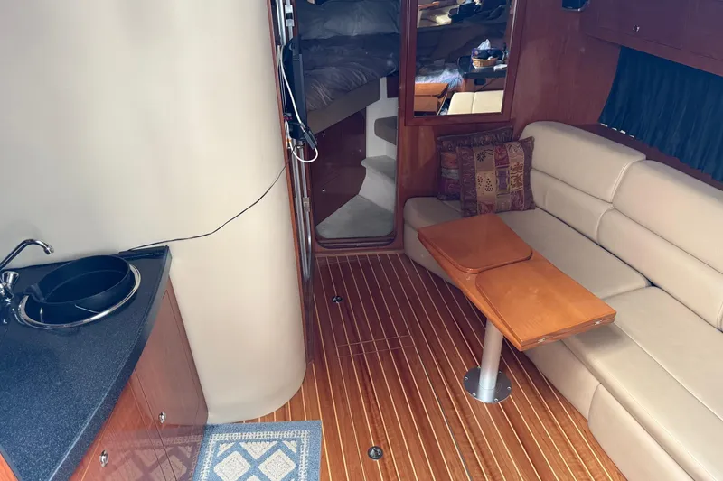 Slide: The Image of 2007 Regal Commodore 3760 IO interior with kitchenette, seating, and wooden flooring. - 10