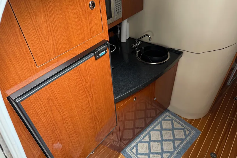 Slide: The Image of 2007 Regal Commodore 3760 IO yacht interior with wood cabinetry and compact kitchenette. - 16