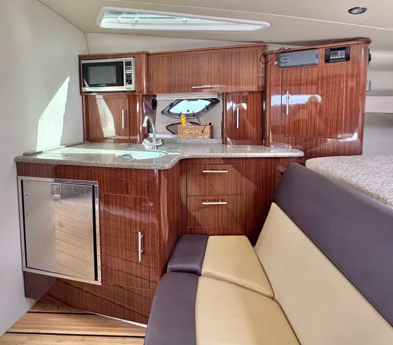 Slide: The Image of 2015 Regal 35 Sport Coupe interior with kitchenette, featuring wood cabinetry and modern appliances. - 21
