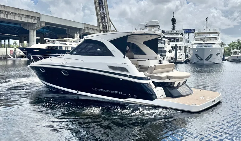 Slide: The Image of 2015 Regal 35 Sport Coupe yacht cruising in a marina, surrounded by other boats. - 5