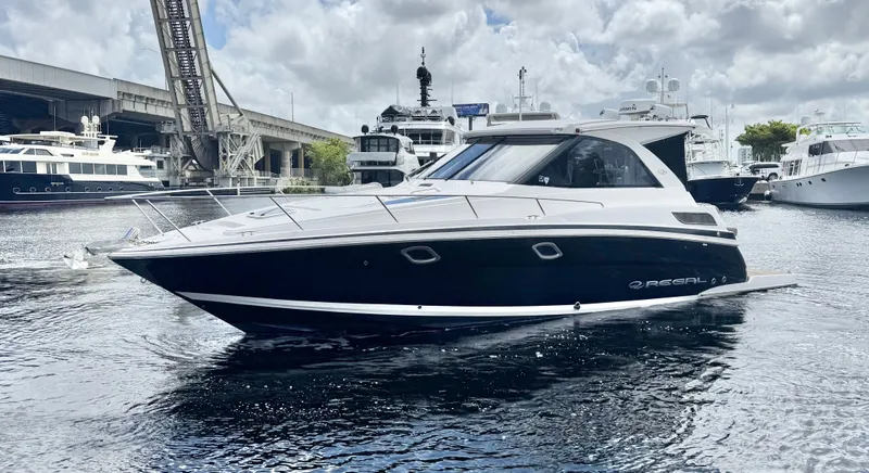 Slide: The Image of 2015 Regal 35 Sport Coupe yacht docked in a marina, surrounded by other boats. - 7