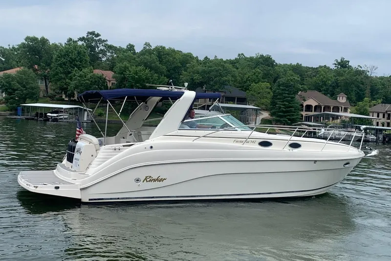 The Image of 2002 Rinker 342 Fiesta Vee boat on a serene lake with lush greenery. - 0