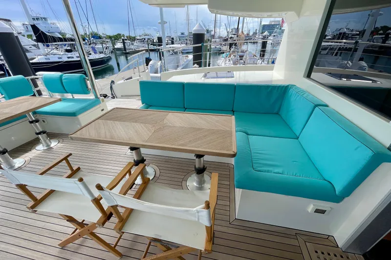 Slide: The Image of Luxurious Serenity 64 yacht deck with turquoise seating and wooden tables, docked at a marina. - 22