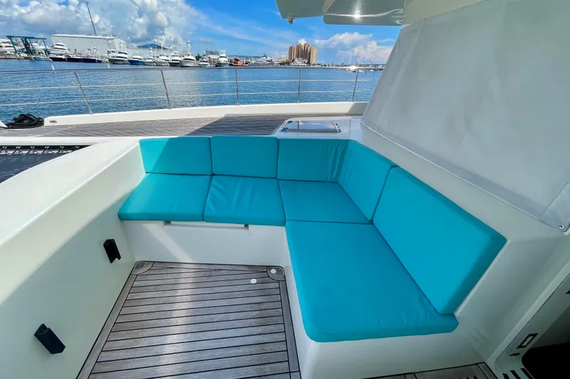 Slide: The Image of Luxurious Serenity 64 yacht deck with turquoise seating, overlooking marina and blue sky. - 27